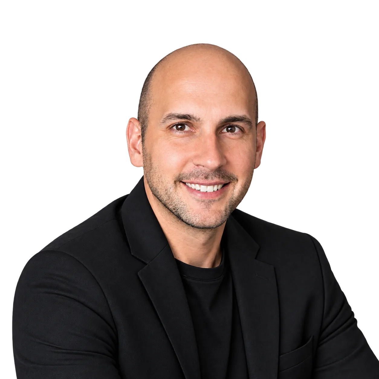 Smiling bald man with light beard wearing a black blazer and black shirt, posing with crossed arms on a transparent background.